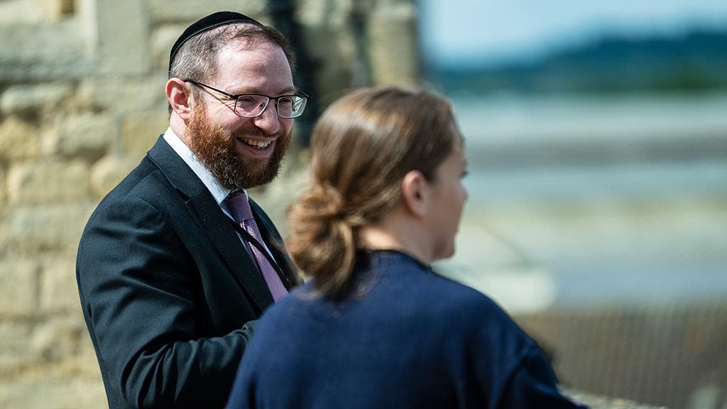 A smiling participant talks with a colleague outside St George's House, Windsor Castle