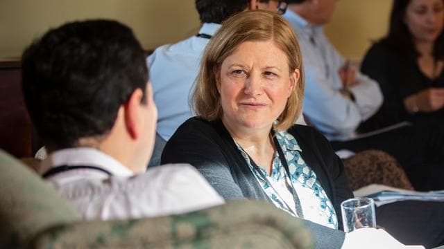 A participant listens attentively to a colleague across the table during a session
