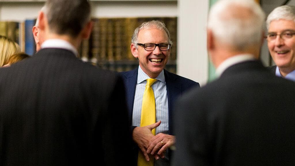 A smiling leader in a yellow tie talks with colleagues in a library